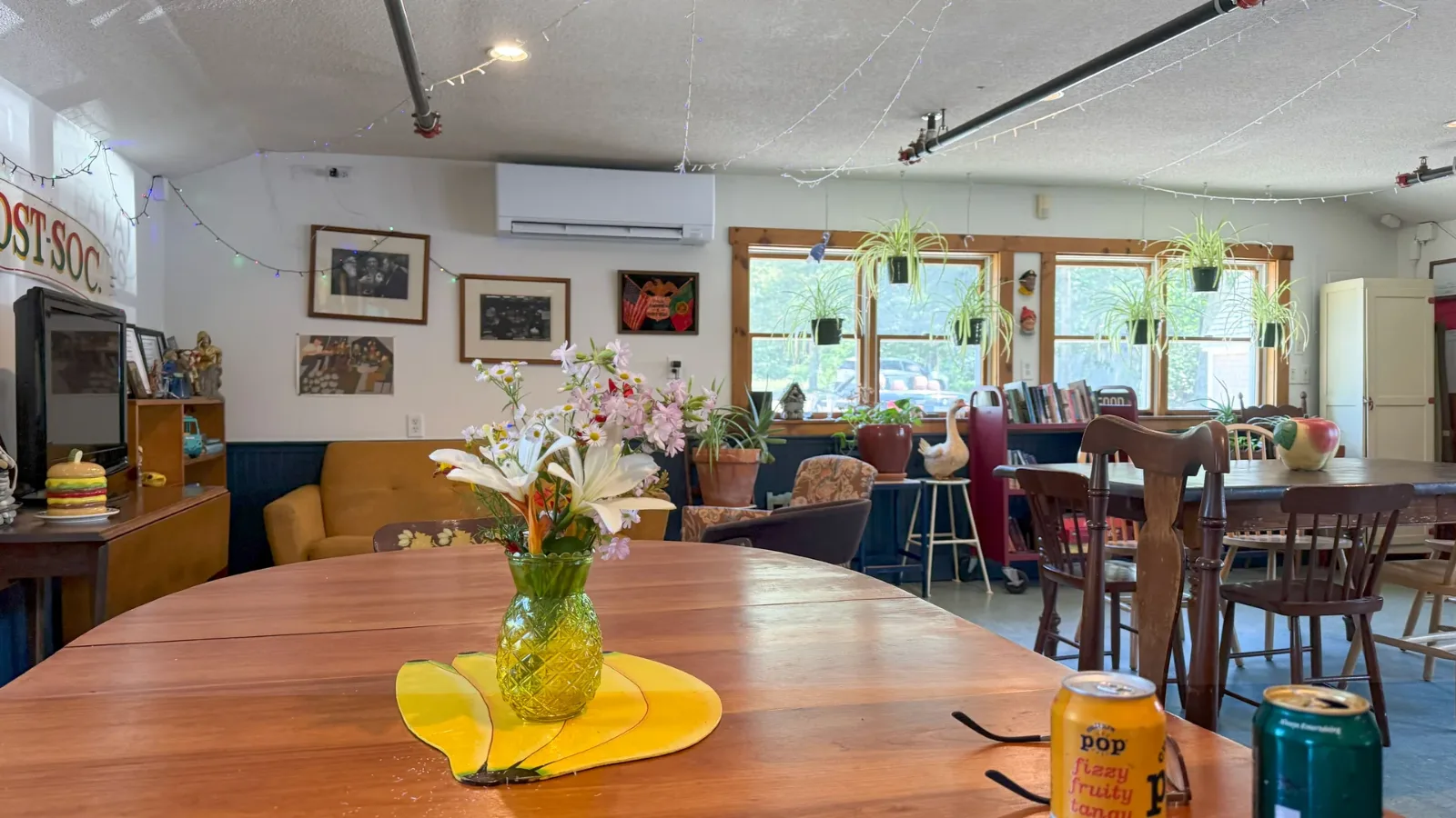 The P.O. Club room at Mo's Lunch, wooden tables, plants in the windows and flowers on the table