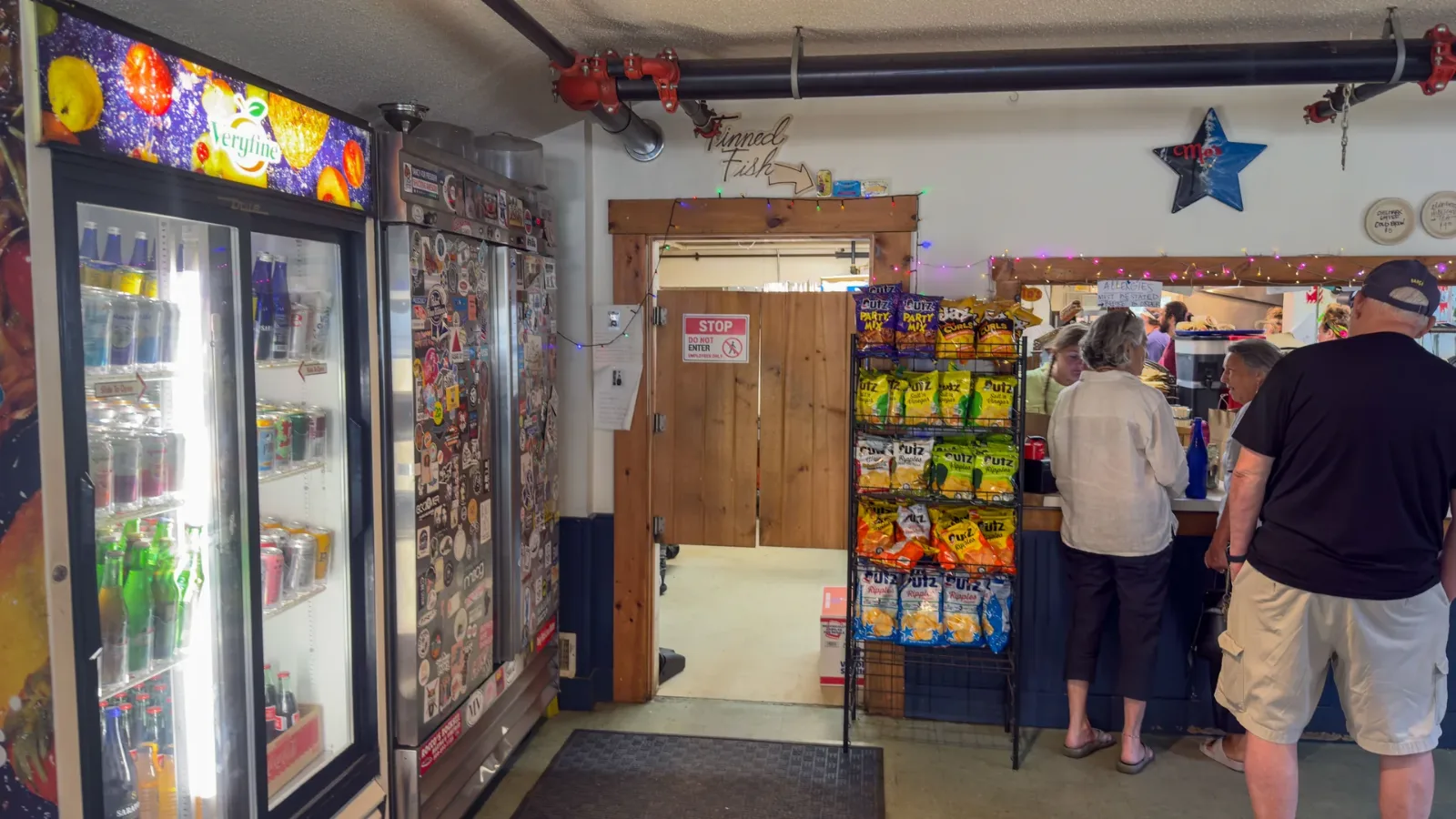 The counter at Mo's Lunch, drinks cooler and shelves of snacks, customers waiting to order