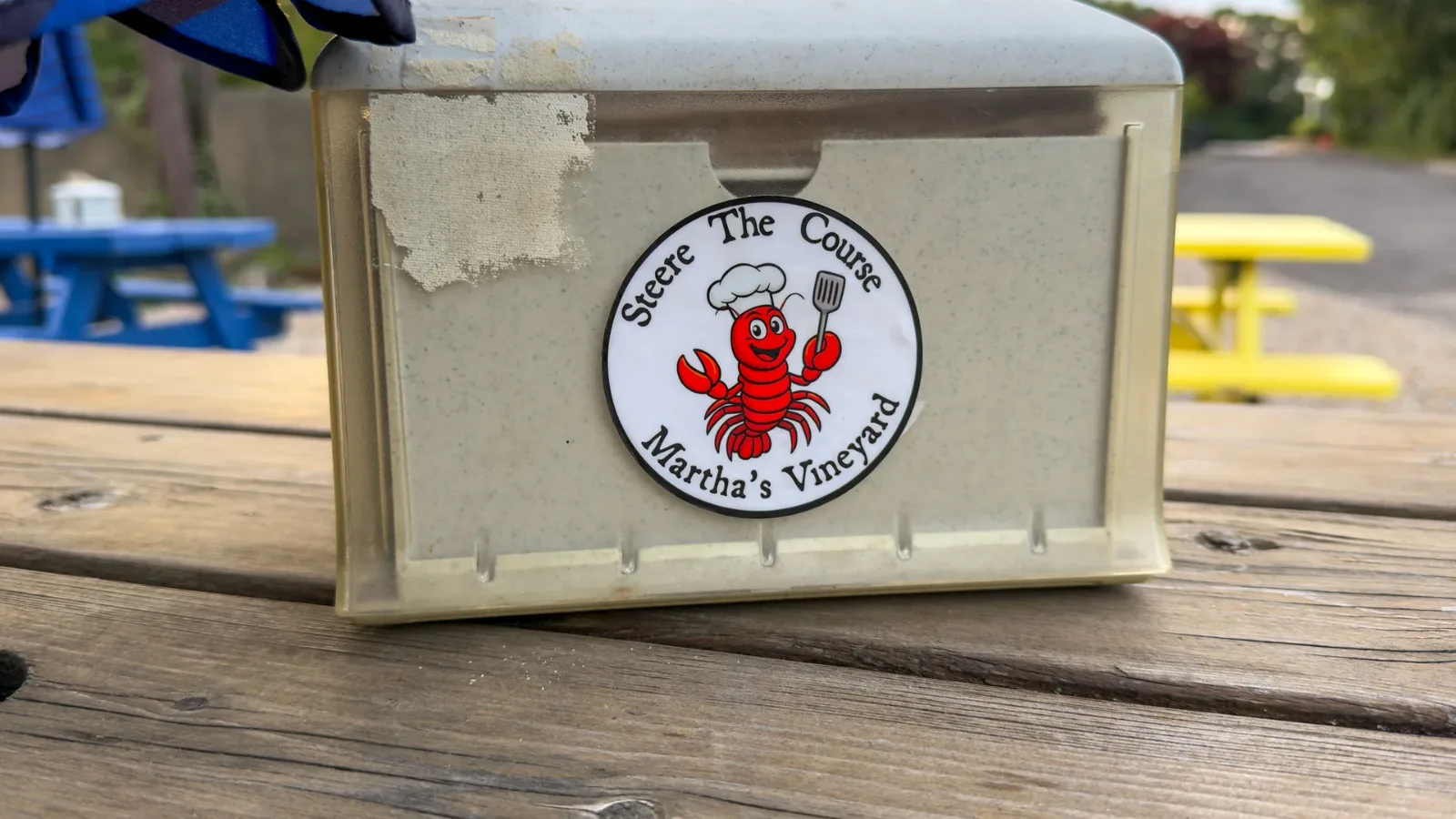 The Steere The Course lobster logo on a cooler beside the mini golf picnic tables
